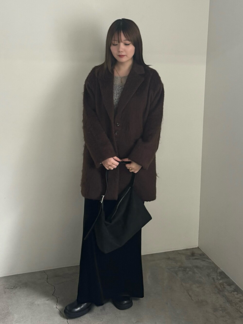 ブラウン系のテーラードジャケット、グレー系のニット/セーター、ブラック系のスカートを着用したレディースの秋コーディネートの3枚目の写真