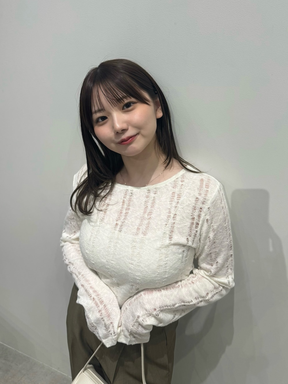 ブラウン系のスラックス、ホワイト系のハンドバッグ、ホワイト系のキャミソールを着用したレディースの春コーディネートの5枚目の写真