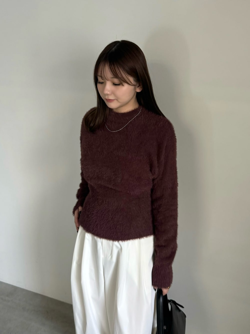 ブラウン系のニット/セーター、ホワイト系のその他パンツ、ブラック系のハンドバッグを着用したレディースの秋コーディネートの3枚目の写真
