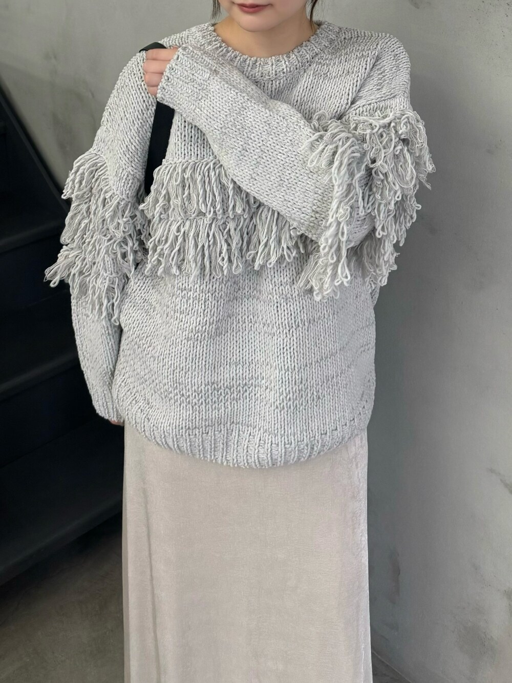 グレー系のニット/セーター、ホワイト系のスカート、ブラック系のショルダーバッグを着用したレディースの秋コーディネートの4枚目の写真