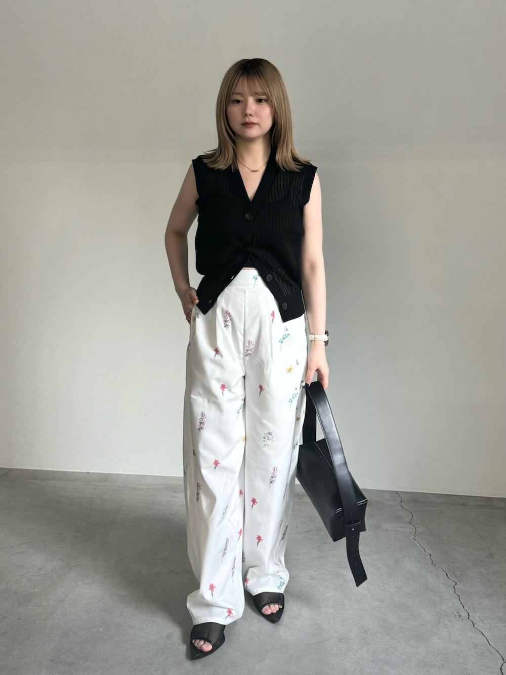 ブラック系のキャミソール、ブラック系のベスト、ブラック系のショルダーバッグを着用したレディースの春コーディネートの2枚目の写真