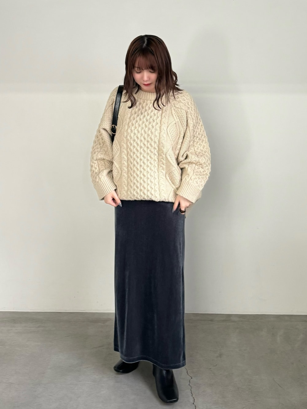 グレー系のスカート、ホワイト系のニット/セーター、ブラック系のハンドバッグを着用したレディースの秋コーディネートの3枚目の写真