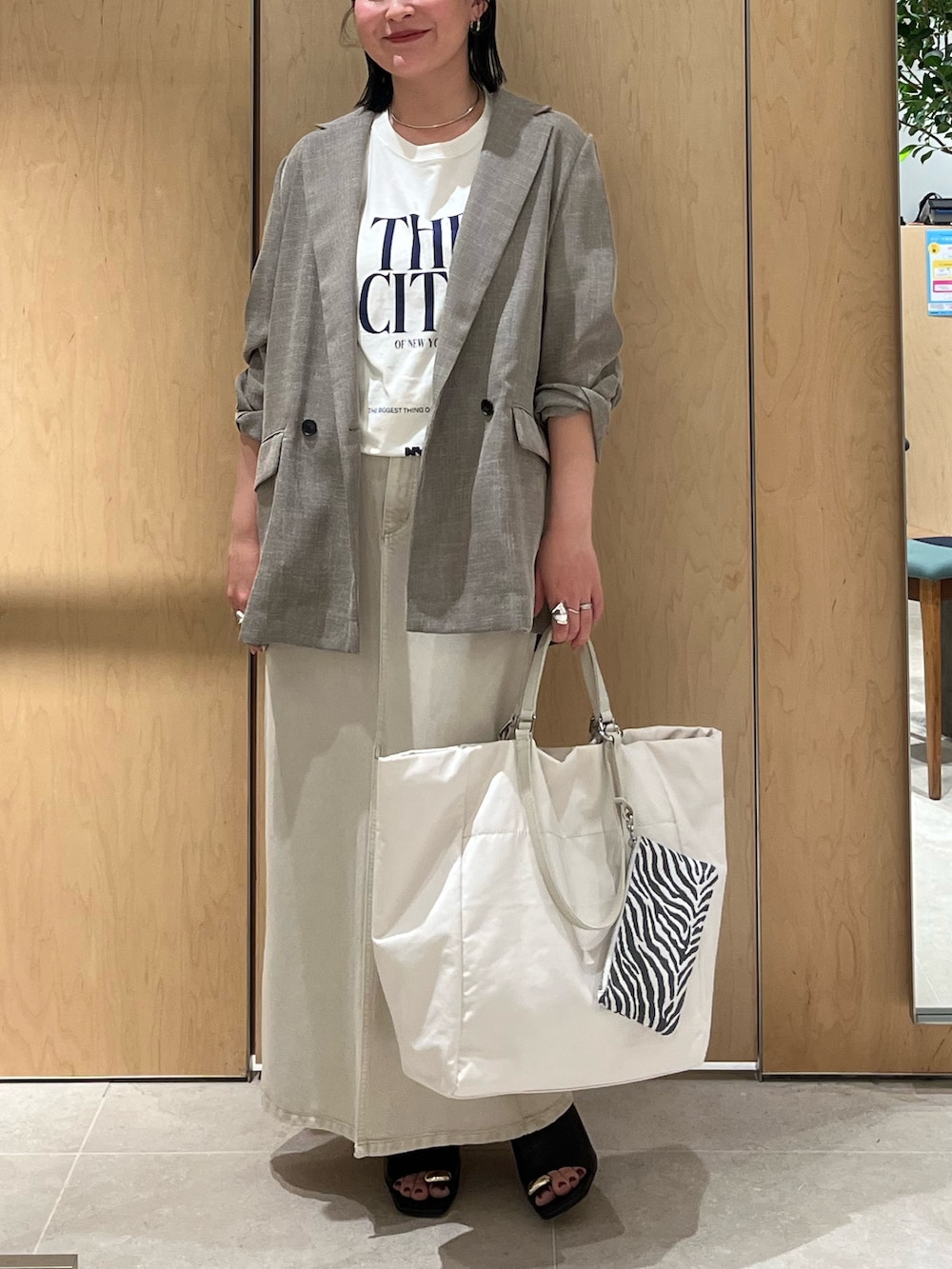 ホワイト系のスカート、ホワイト系のトートバッグ、ブラック系のテーラードジャケットを着用したレディースの春コーディネートの2枚目の写真