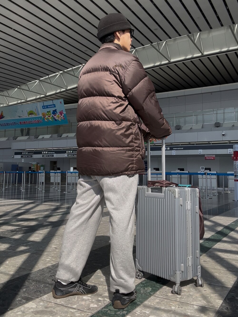 ブラック系のシューズ、グレー系のスウェットパンツ、ブラウン系のダウンジャケット/コートを着用したメンズの春コーディネートの2枚目の写真