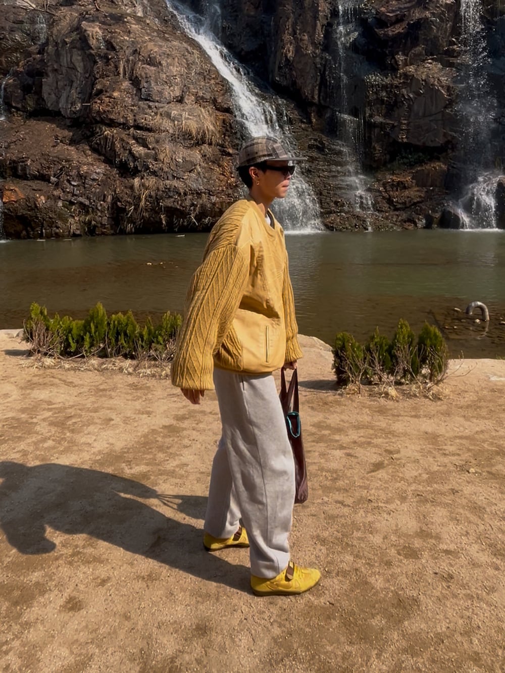 イエロー系のシューズ、イエロー系のニット/セーター、グレー系のスウェットパンツを着用したメンズの春コーディネートの2枚目の写真