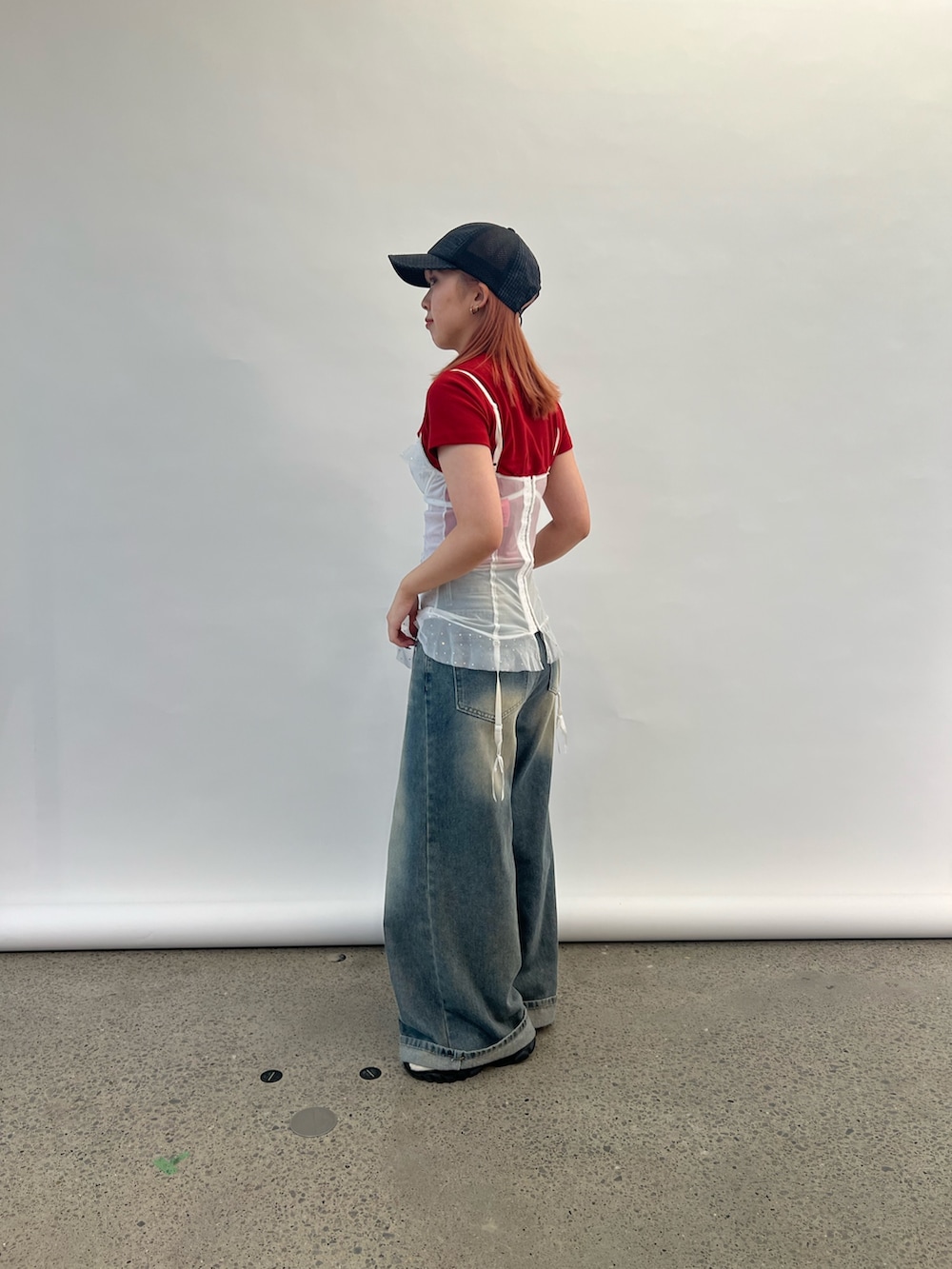 レッド系のTシャツ/カットソー、ブラック系のキャップ、グレー系のヘアバンドを着用したレディースの夏コーディネートの2枚目の写真