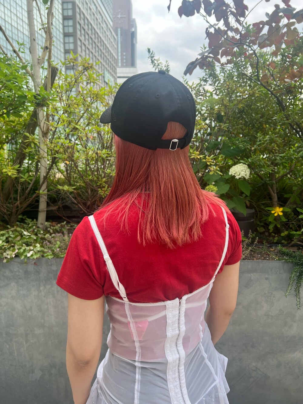 レッド系のTシャツ/カットソー、ブラック系のキャップを着用したレディースの夏コーディネートの3枚目の写真