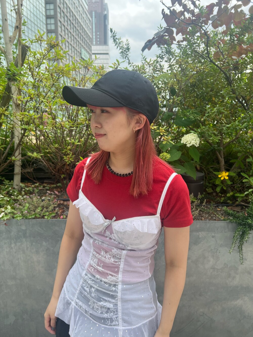 レッド系のTシャツ/カットソー、ブラック系のキャップを着用したレディースの夏コーディネートの2枚目の写真