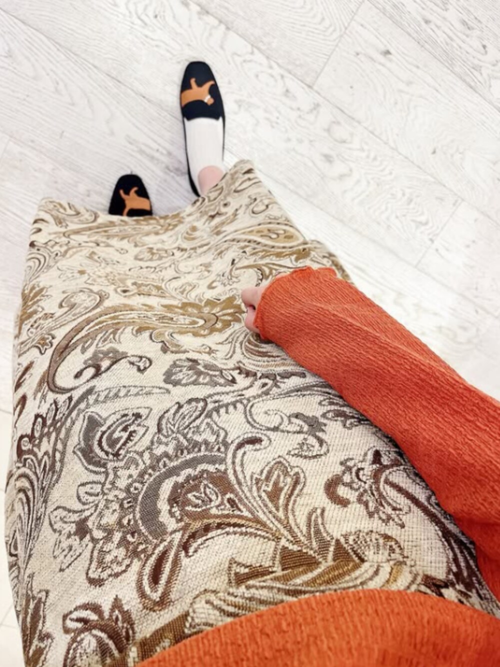 ブラック系のパンプス、オレンジ系のその他トップス、ホワイト系のスカートを着用したレディースの秋コーディネートの3枚目の写真