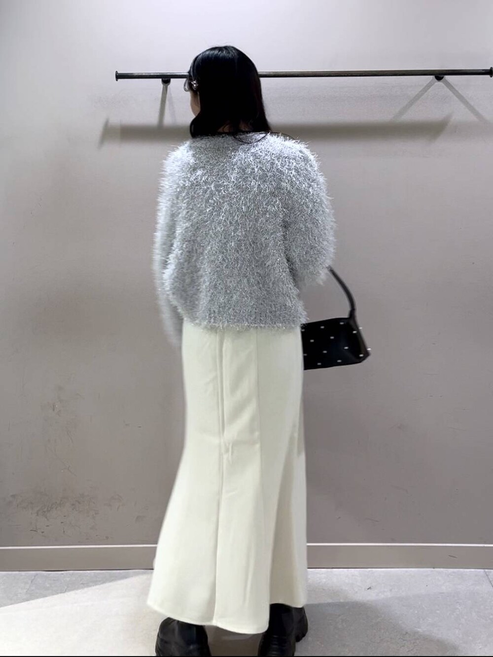 ブラック系のニット/セーター、ブラック系のブーツ、ホワイト系のスカートを着用したレディースの冬コーディネートの3枚目の写真