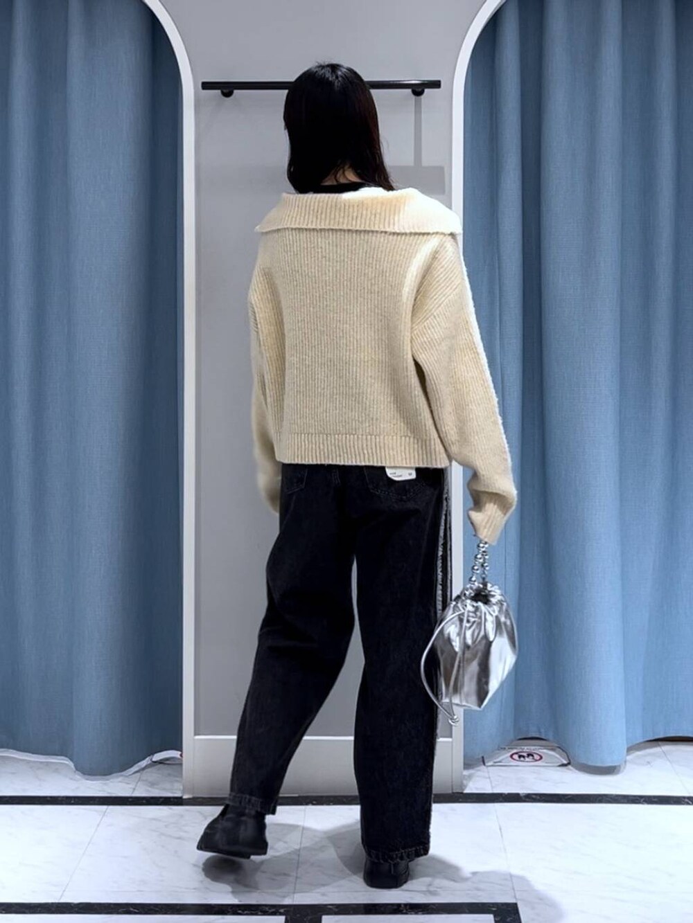 ブラック系のニット/セーター、シルバー系のショルダーバッグ、ブラック系のデニムパンツを着用したレディースの秋コーディネートの3枚目の写真