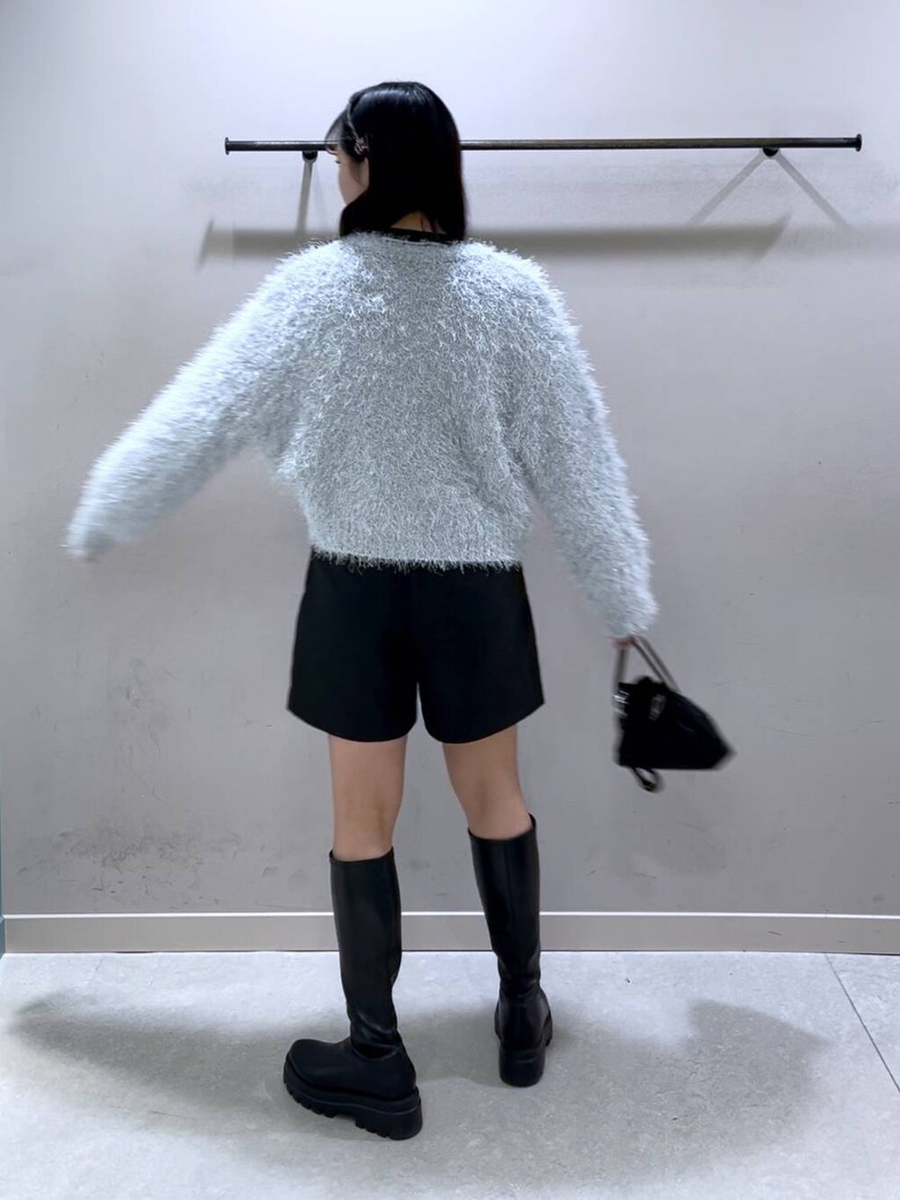 ブラック系のニット/セーター、ブラック系のブーツ、ブラック系のショルダーバッグを着用したレディースの冬コーディネートの3枚目の写真