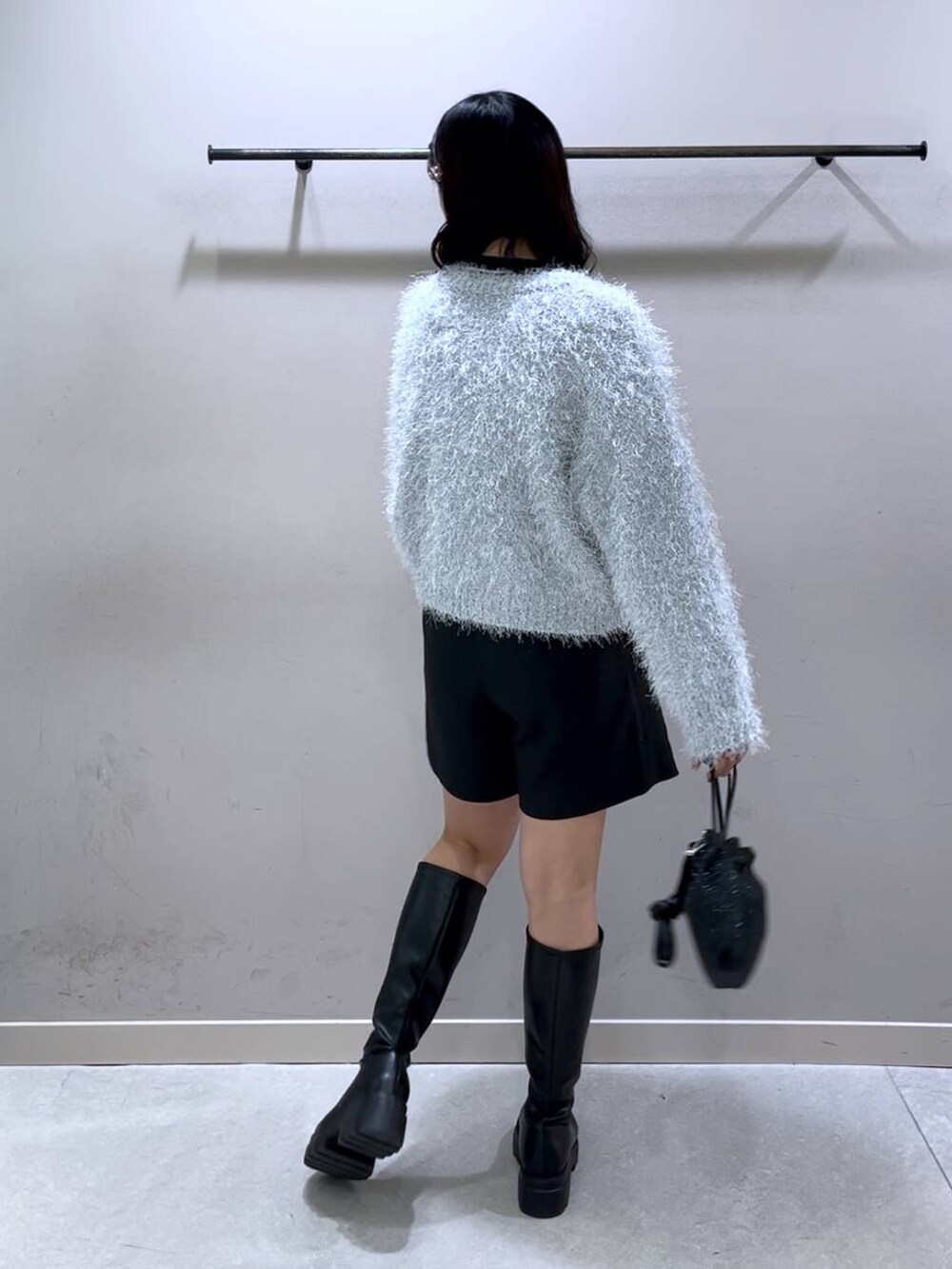 ブラック系のニット/セーター、ブラック系のブーツ、ブラック系のショルダーバッグを着用したレディースの冬コーディネートの2枚目の写真