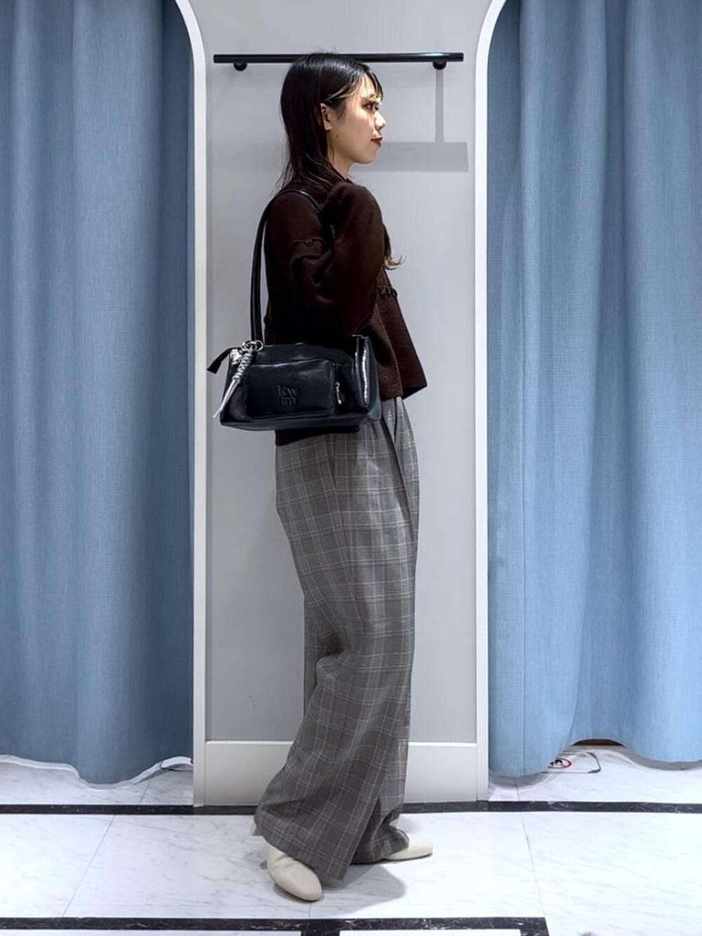 ブラック系のショルダーバッグ、ホワイト系のブーツ、グレー系のスラックスを着用したレディースの冬コーディネートの4枚目の写真