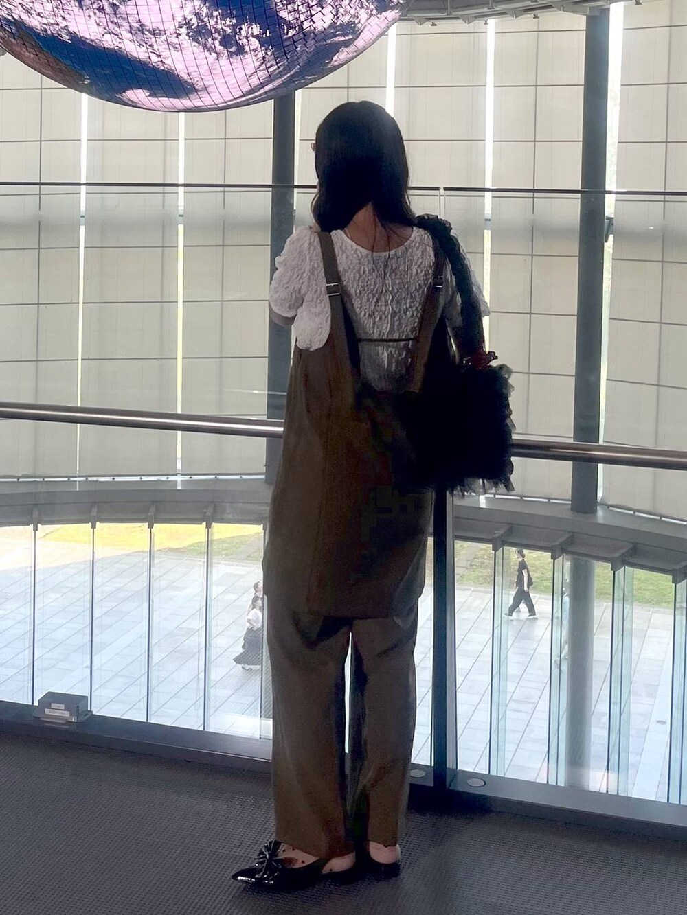 ブラック系のパンプス、ブラウン系のスラックス、ベージュ系のキャミソールを着用したレディースの夏コーディネートの3枚目の写真