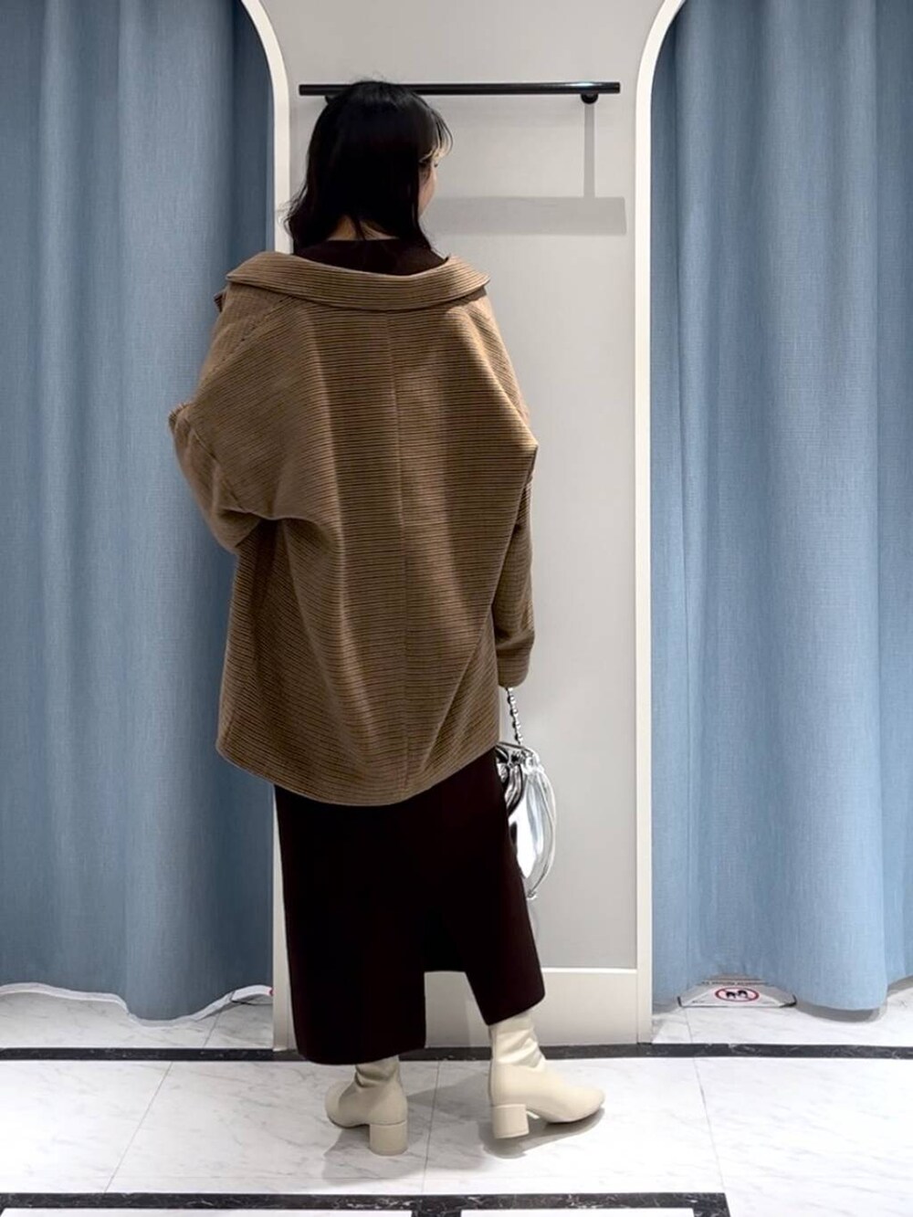 シルバー系のショルダーバッグ、ホワイト系のブーツ、その他のテーラードジャケットを着用したレディースの冬コーディネートの3枚目の写真