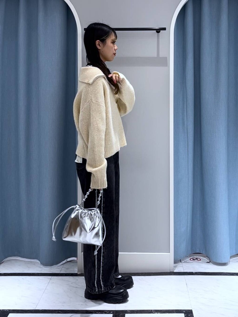 ブラック系のニット/セーター、シルバー系のショルダーバッグ、ブラック系のデニムパンツを着用したレディースの秋コーディネートの5枚目の写真