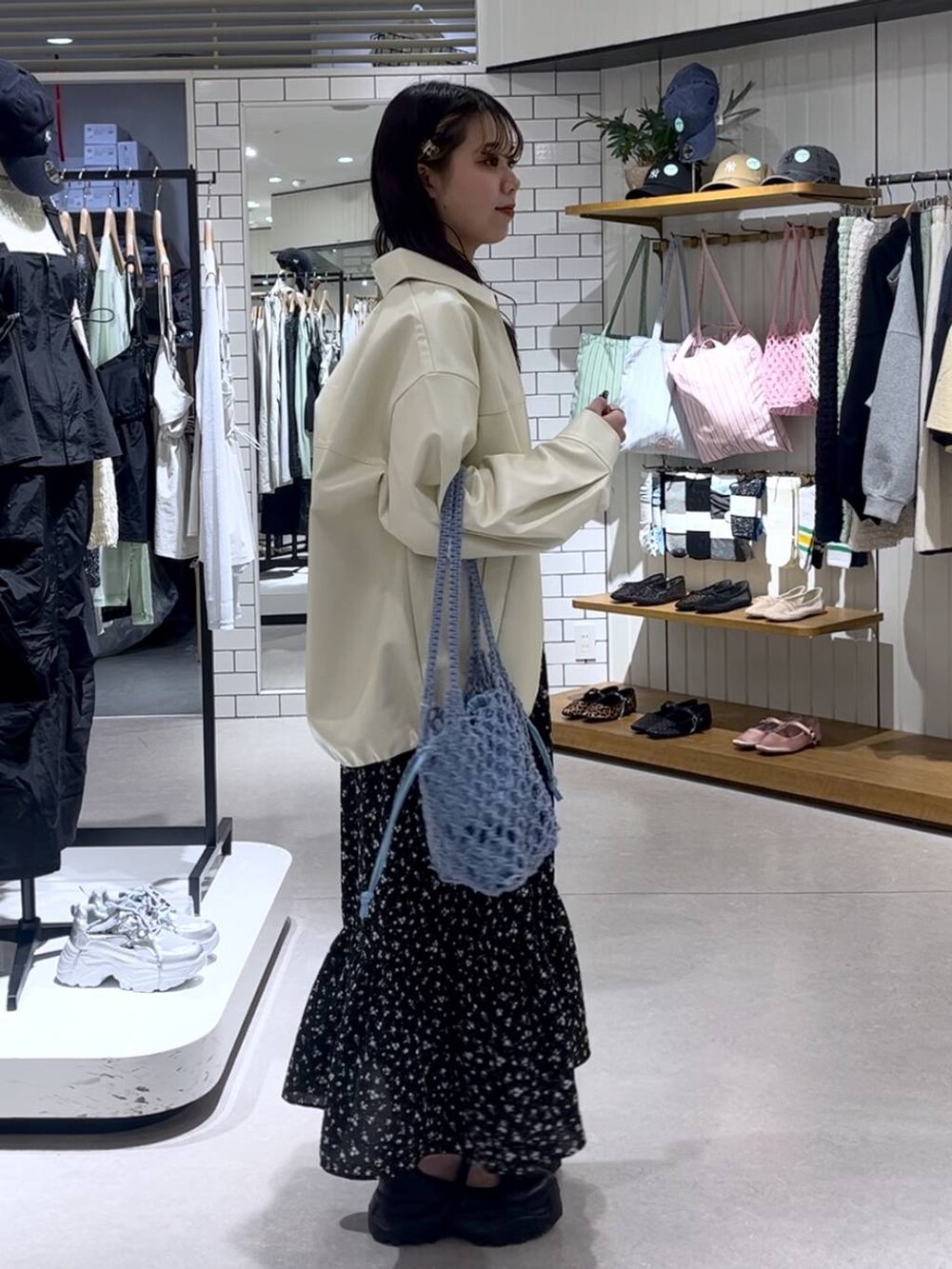 ブラック系のスニーカー、ブルー系のトートバッグ、ホワイト系のブルゾンを着用したレディースの春コーディネートの5枚目の写真