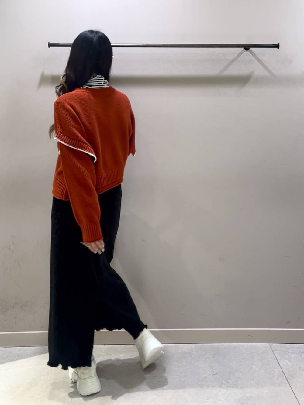 レッド系のニット/セーター、ブラック系のスカート、ホワイト系のスニーカーを着用したレディースの冬コーディネートの2枚目の写真