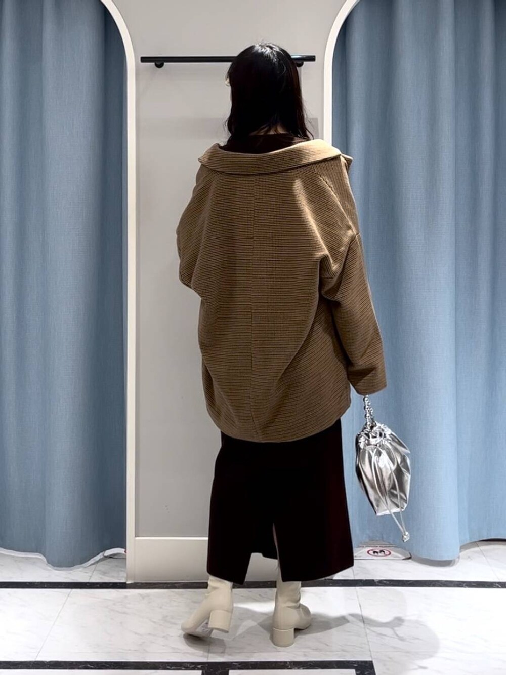 シルバー系のショルダーバッグ、ホワイト系のブーツ、その他のテーラードジャケットを着用したレディースの冬コーディネートの4枚目の写真