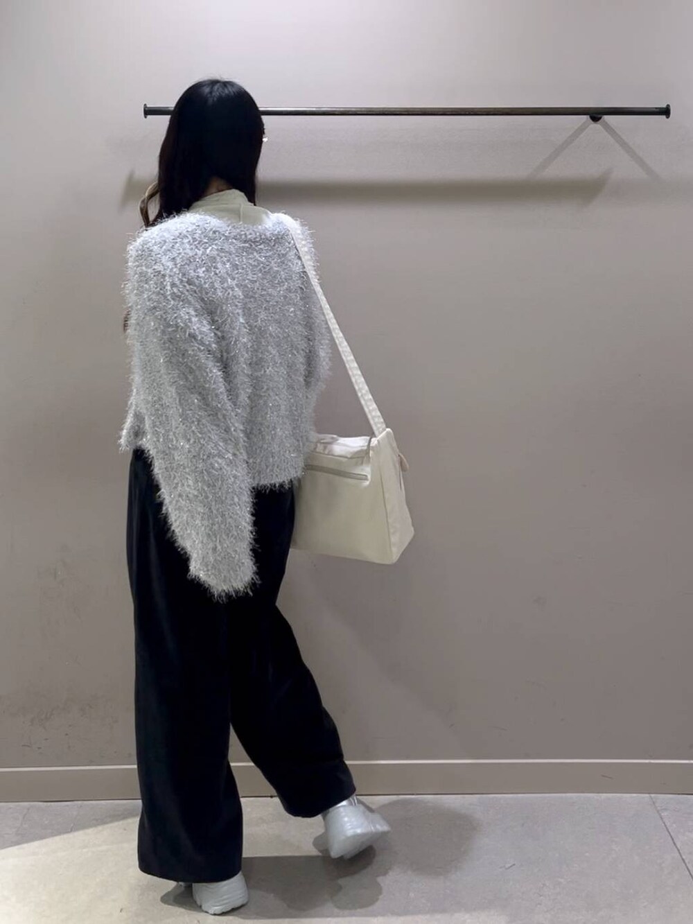 ホワイト系のショルダーバッグ、ホワイト系のTシャツ/カットソー、シルバー系のスニーカーを着用したレディースの冬コーディネートの2枚目の写真