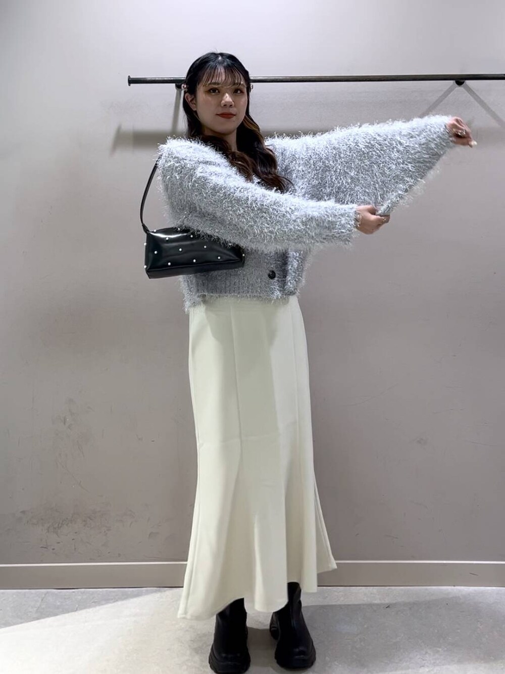 ブラック系のニット/セーター、ブラック系のブーツ、ホワイト系のスカートを着用したレディースの冬コーディネートの6枚目の写真