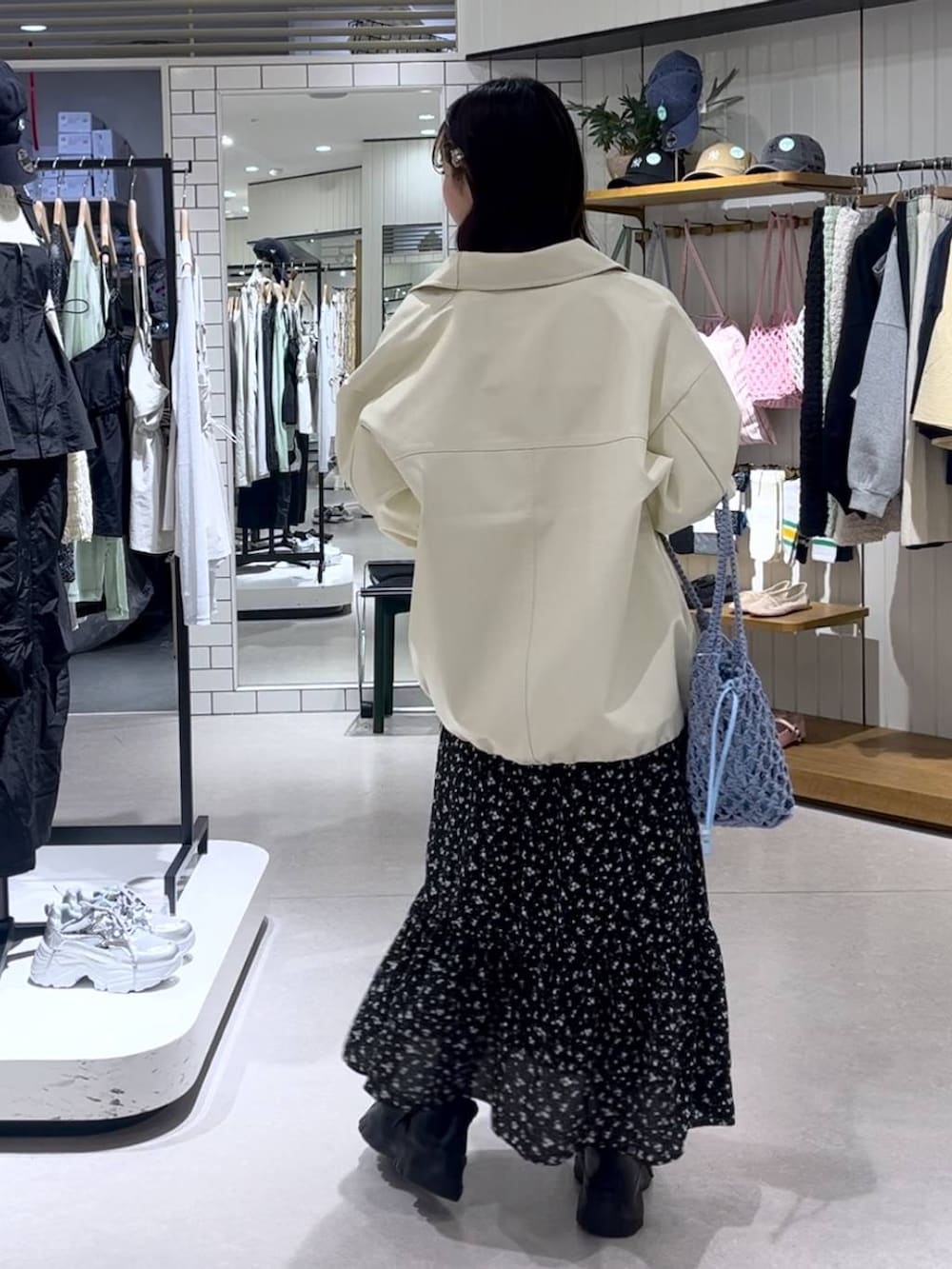 ブラック系のスニーカー、ブルー系のトートバッグ、ホワイト系のブルゾンを着用したレディースの春コーディネートの4枚目の写真