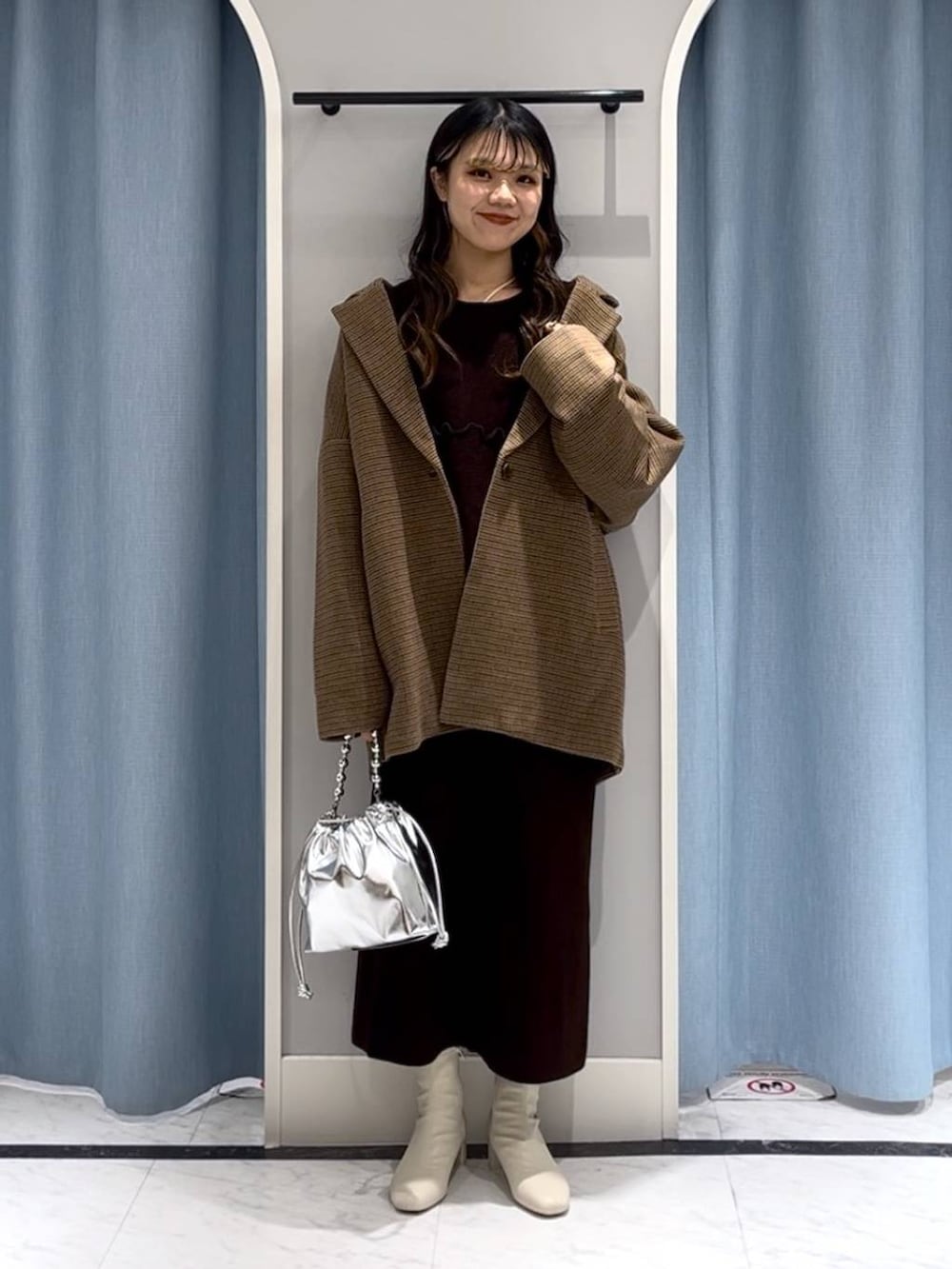 シルバー系のショルダーバッグ、ホワイト系のブーツ、その他のテーラードジャケットを着用したレディースの冬コーディネートの6枚目の写真