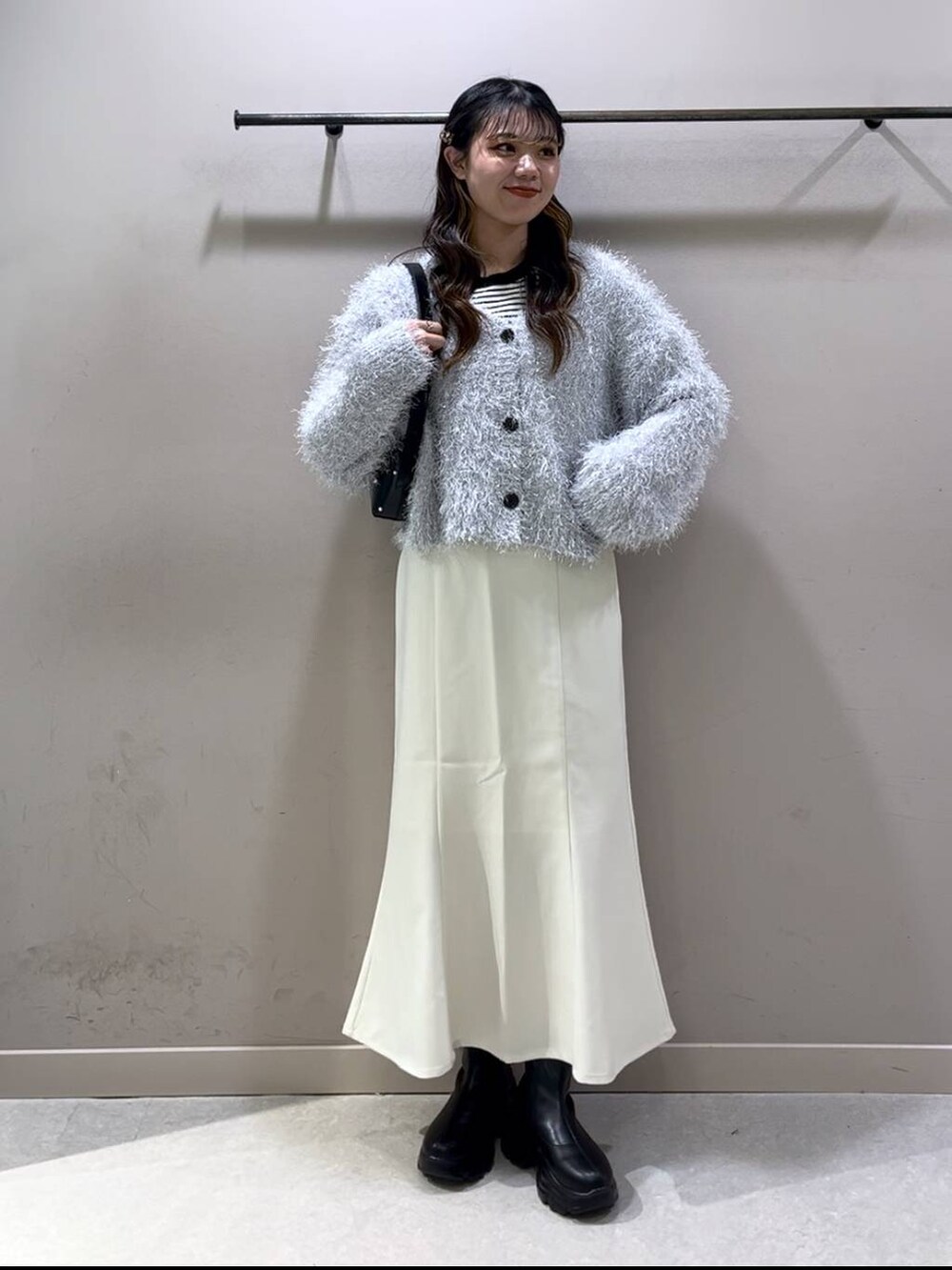 ブラック系のニット/セーター、ブラック系のブーツ、ホワイト系のスカートを着用したレディースの冬コーディネートの7枚目の写真