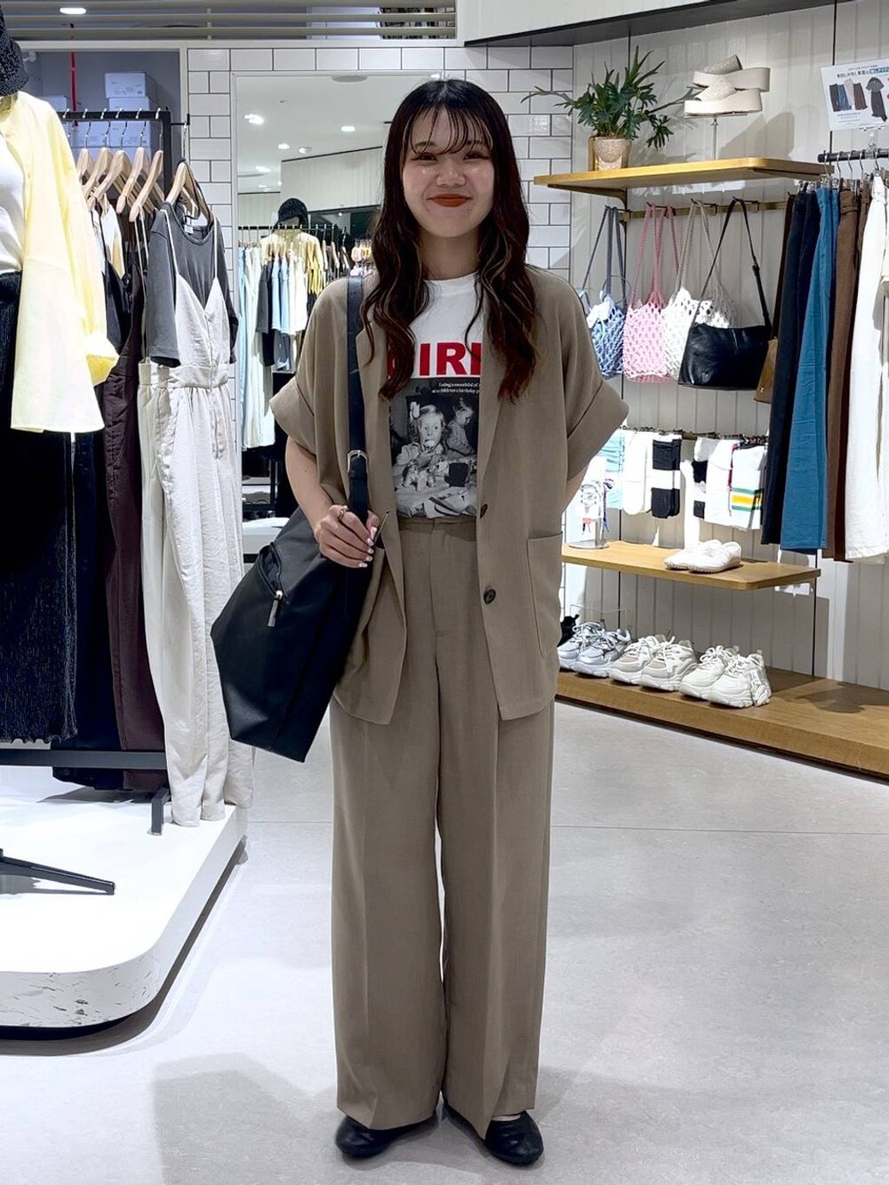 ブラック系のショルダーバッグ、ブラック系のスニーカー、ホワイト系のTシャツ/カットソーを着用したレディースの夏コーディネートの4枚目の写真