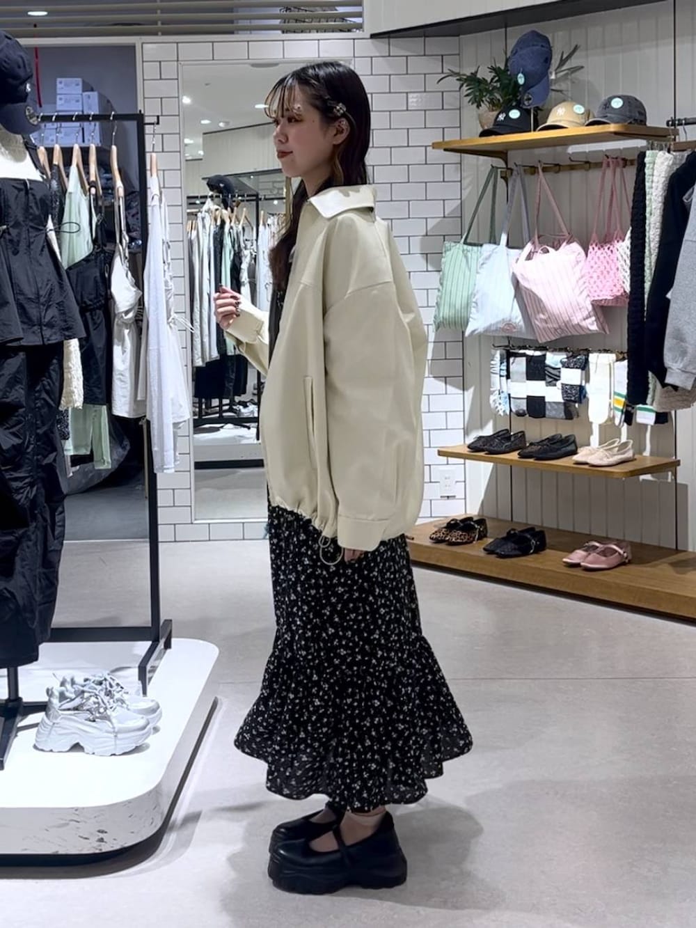 ブラック系のスニーカー、ブルー系のトートバッグ、ホワイト系のブルゾンを着用したレディースの春コーディネートの2枚目の写真