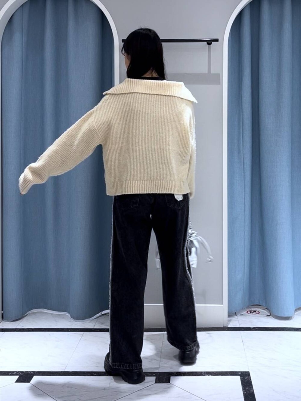 ブラック系のニット/セーター、シルバー系のショルダーバッグ、ブラック系のデニムパンツを着用したレディースの秋コーディネートの2枚目の写真