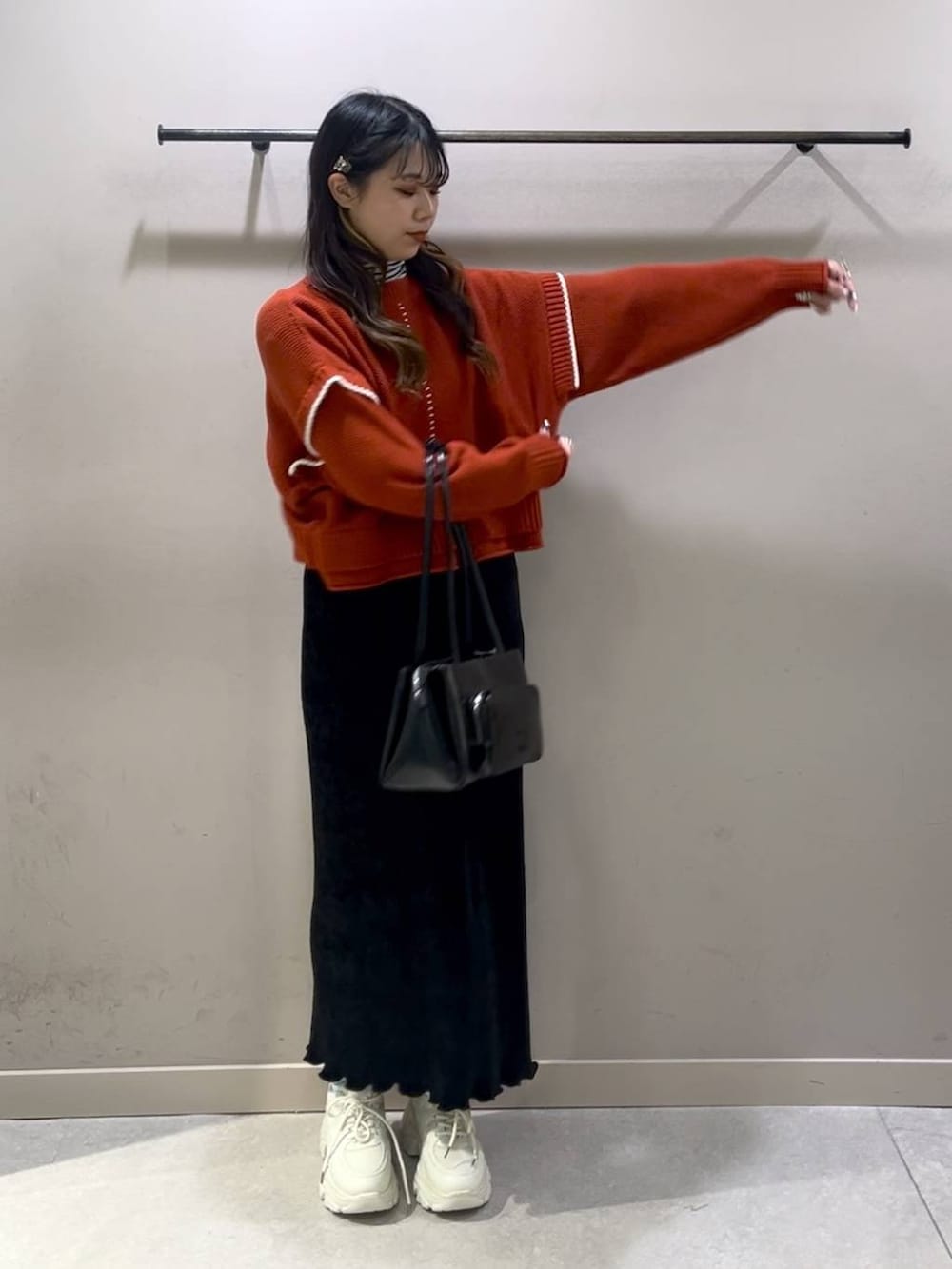 レッド系のニット/セーター、ブラック系のスカート、ホワイト系のスニーカーを着用したレディースの冬コーディネートの6枚目の写真