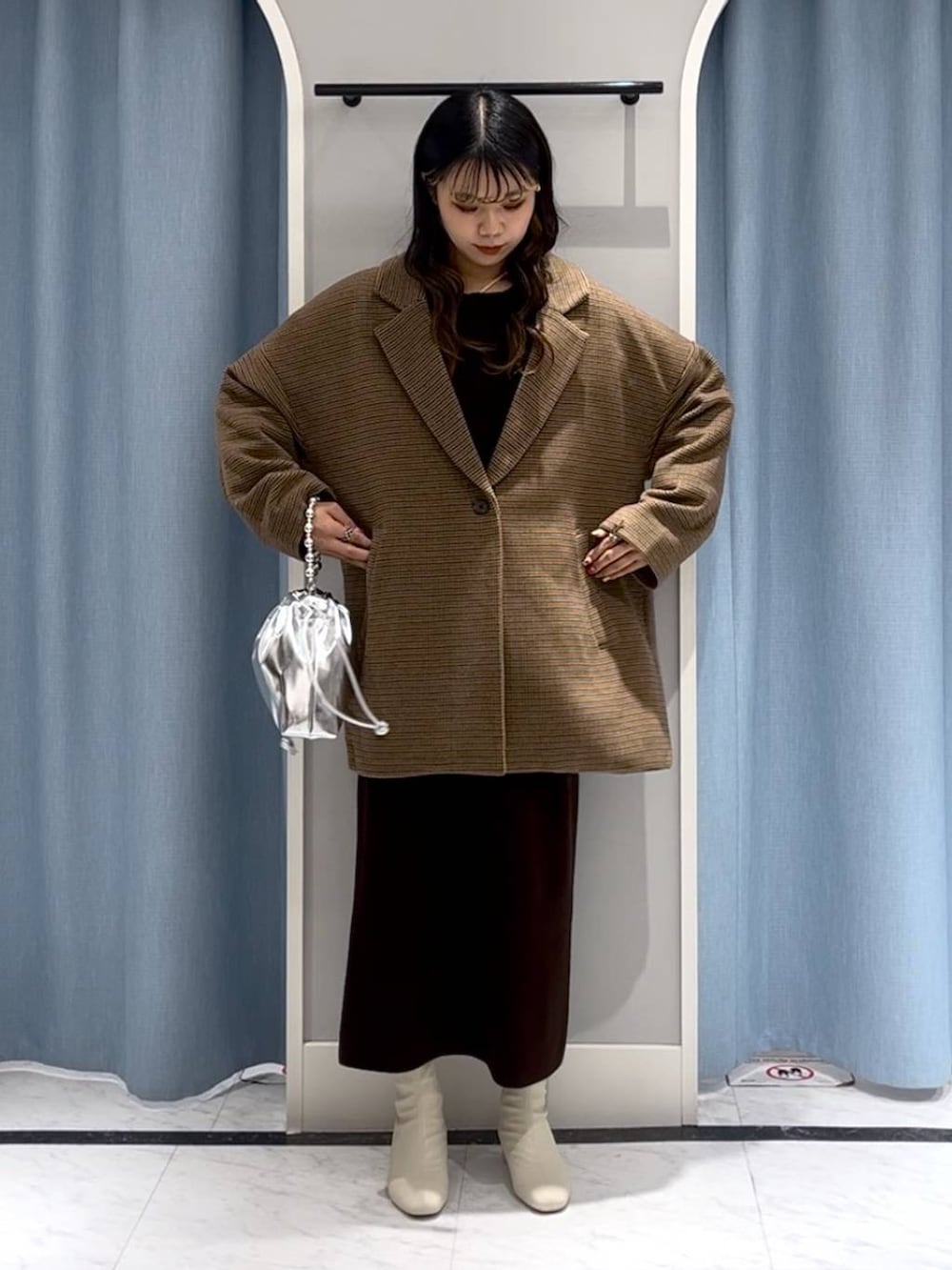 シルバー系のショルダーバッグ、ホワイト系のブーツ、その他のテーラードジャケットを着用したレディースの冬コーディネートの7枚目の写真