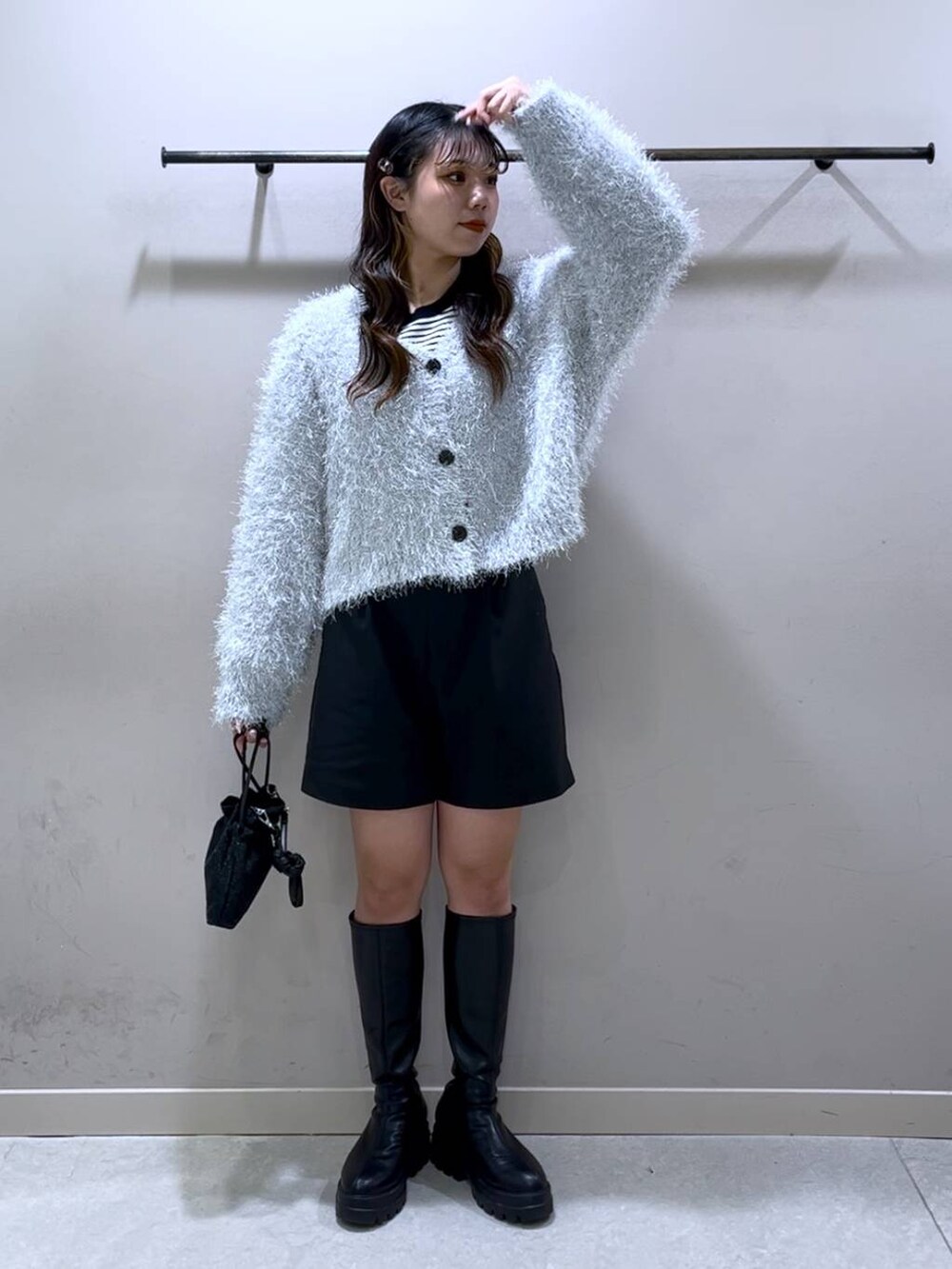 ブラック系のニット/セーター、ブラック系のブーツ、ブラック系のショルダーバッグを着用したレディースの冬コーディネートの8枚目の写真