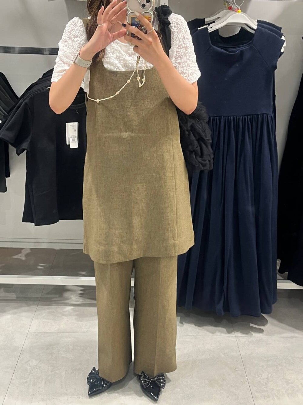 ブラック系のパンプス、ブラウン系のスラックス、ベージュ系のキャミソールを着用したレディースの夏コーディネートの4枚目の写真