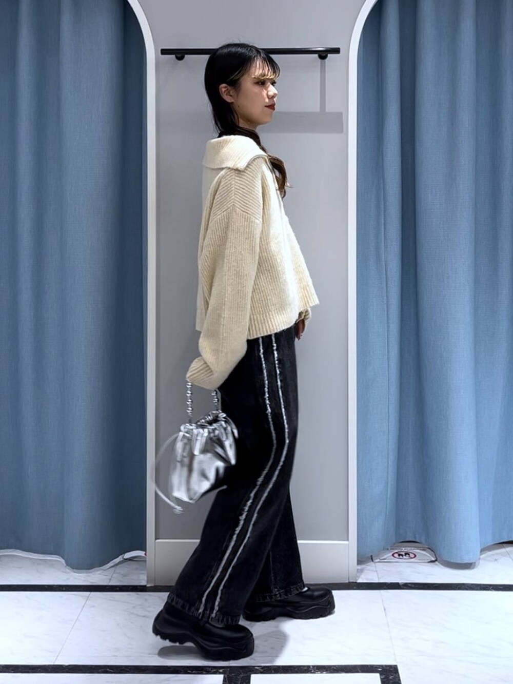 ブラック系のニット/セーター、シルバー系のショルダーバッグ、ブラック系のデニムパンツを着用したレディースの秋コーディネートの6枚目の写真