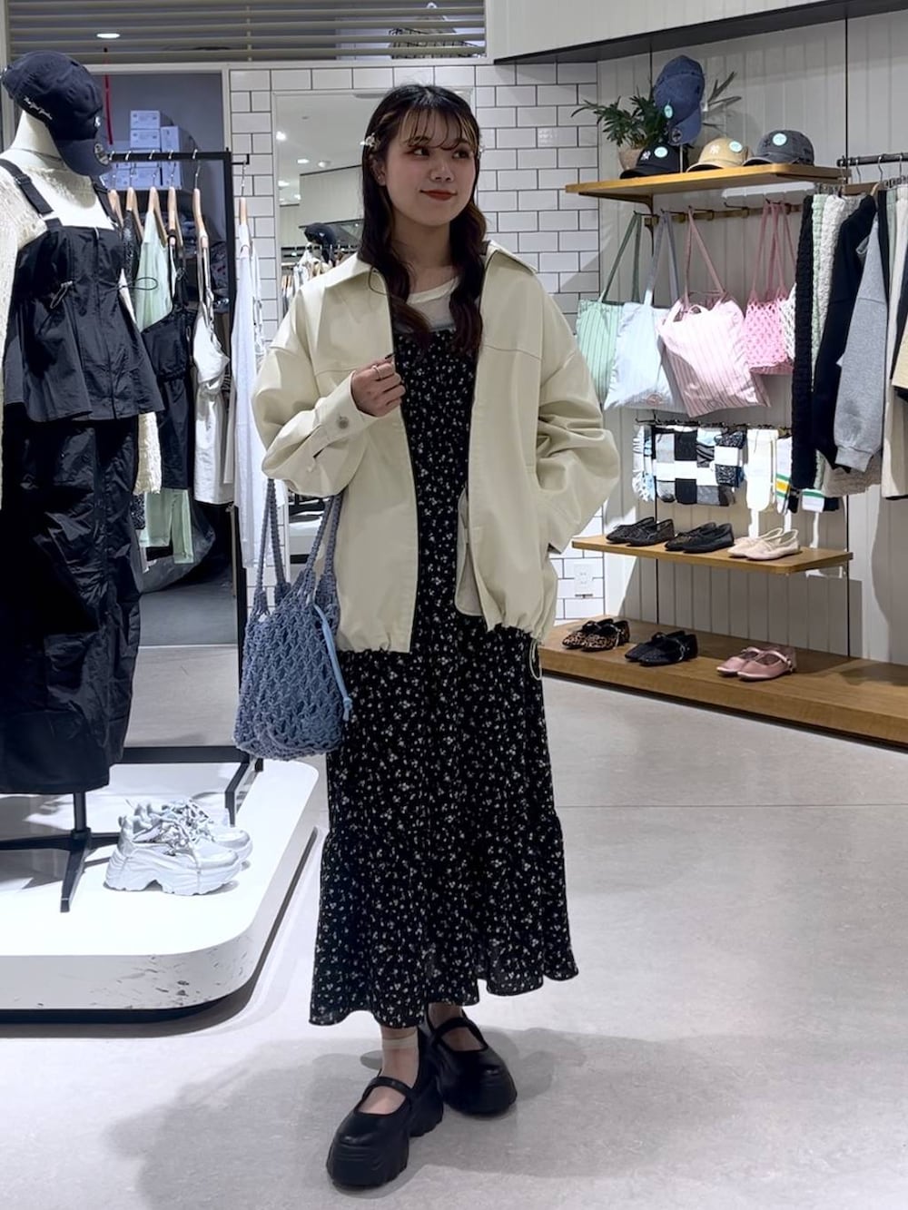 ブラック系のスニーカー、ブルー系のトートバッグ、ホワイト系のブルゾンを着用したレディースの春コーディネートの7枚目の写真