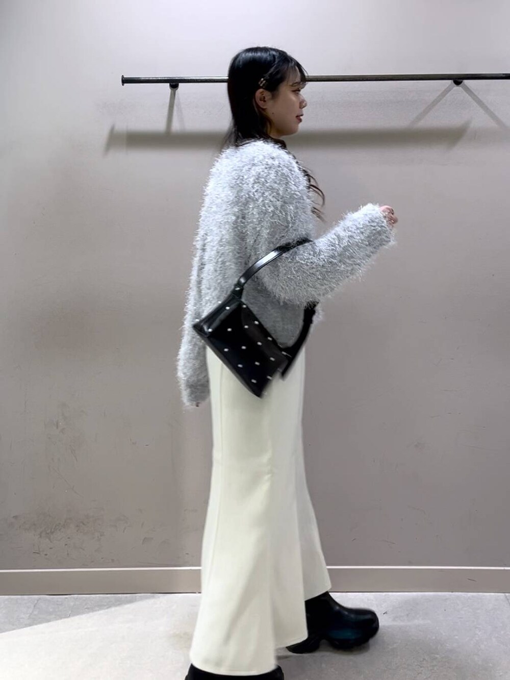 ブラック系のニット/セーター、ブラック系のブーツ、ホワイト系のスカートを着用したレディースの冬コーディネートの4枚目の写真