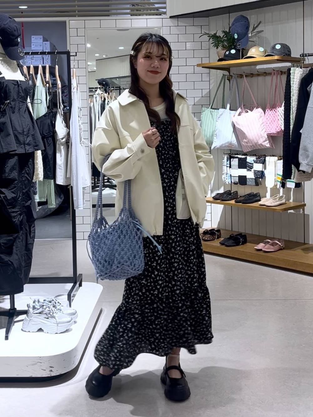 ブラック系のスニーカー、ブルー系のトートバッグ、ホワイト系のブルゾンを着用したレディースの春コーディネートの6枚目の写真