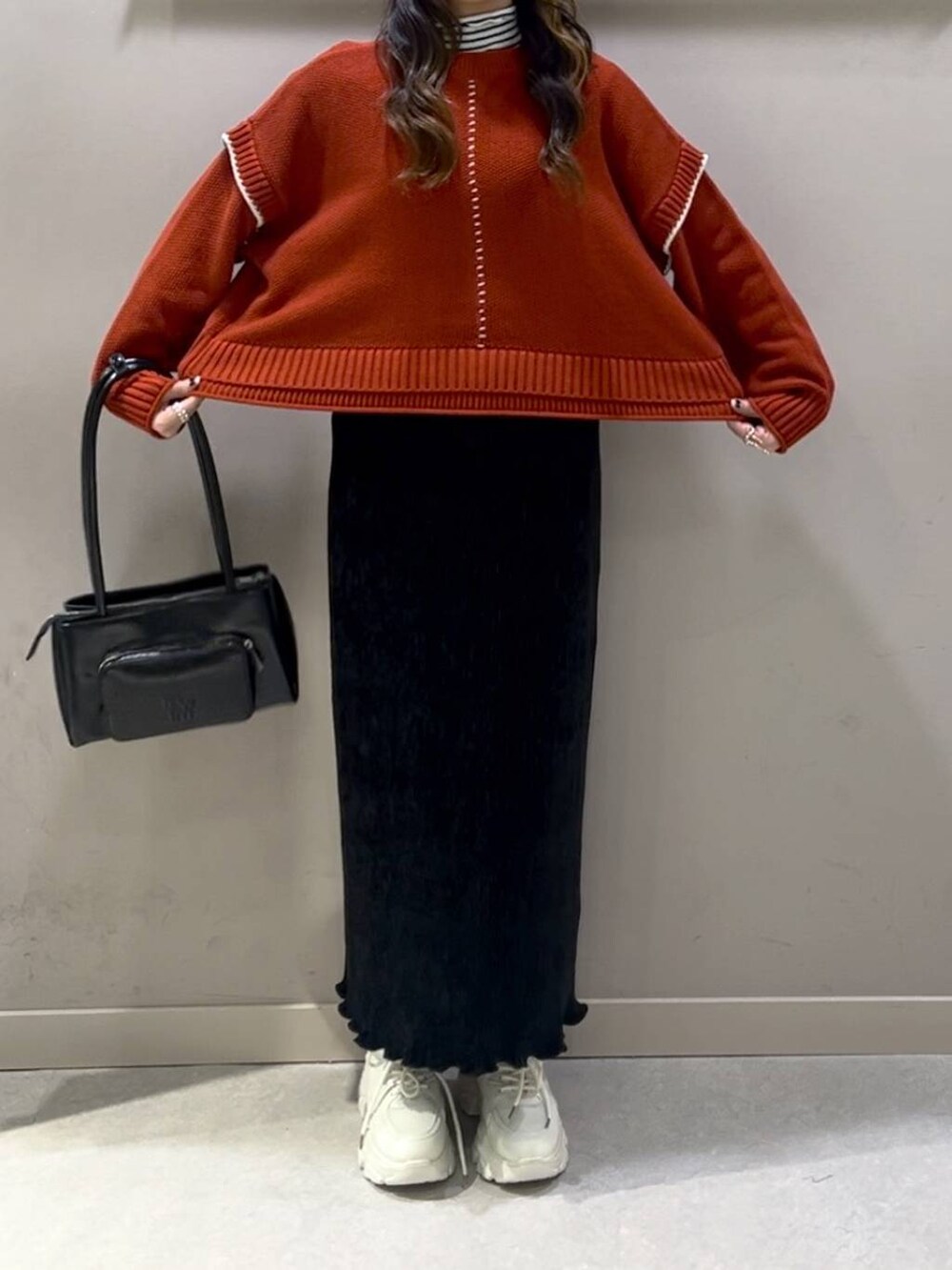 レッド系のニット/セーター、ブラック系のスカート、ホワイト系のスニーカーを着用したレディースの冬コーディネートの5枚目の写真