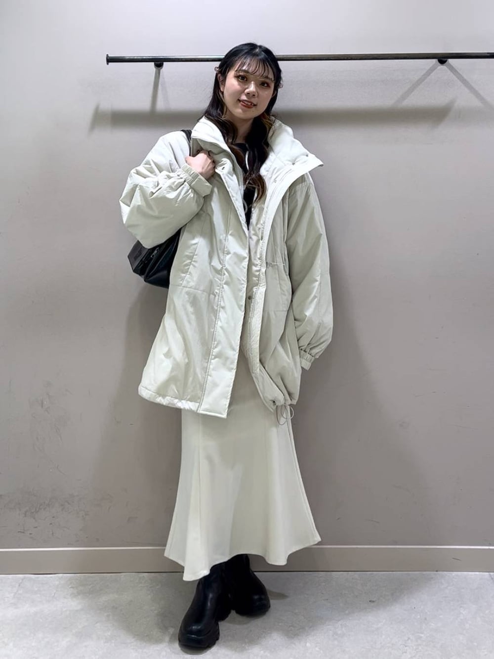 ホワイト系のその他アウター、ブラック系のブーツ、ホワイト系のスカートを着用したレディースの冬コーディネートの7枚目の写真