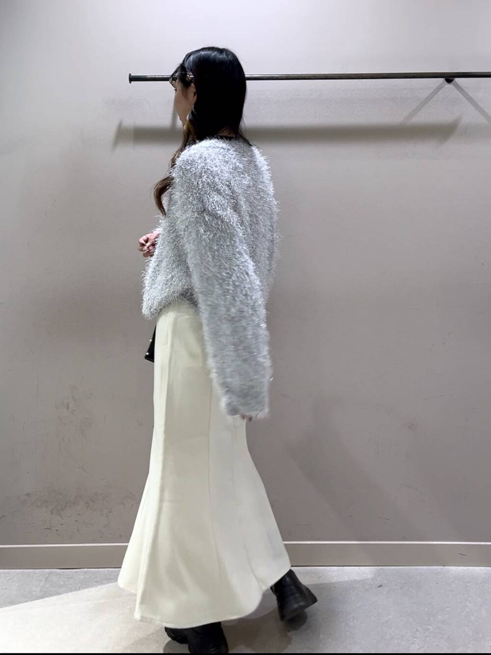 ブラック系のニット/セーター、ブラック系のブーツ、ホワイト系のスカートを着用したレディースの冬コーディネートの2枚目の写真