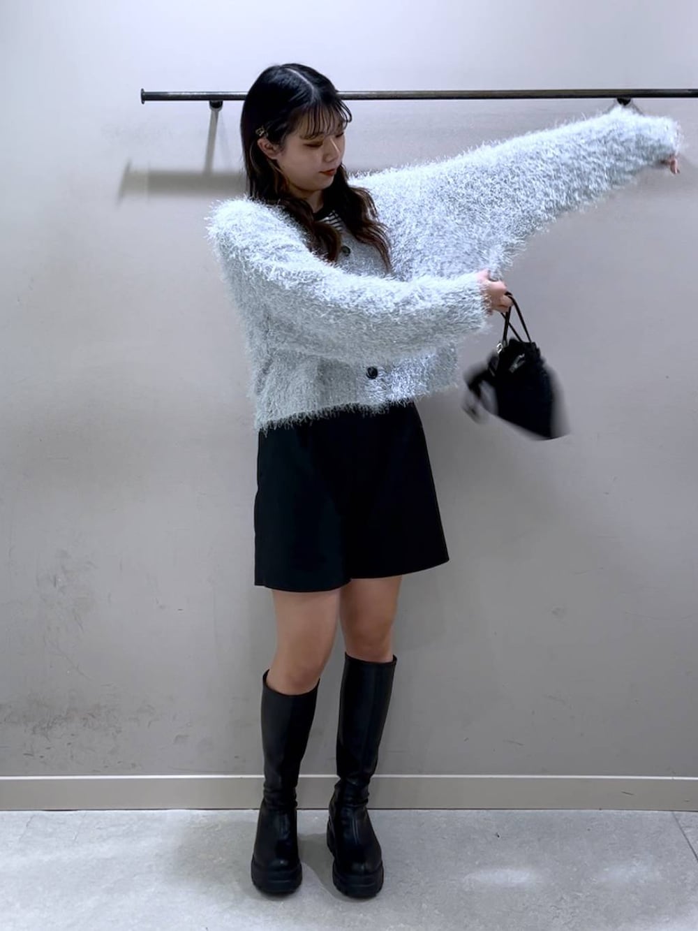 ブラック系のニット/セーター、ブラック系のブーツ、ブラック系のショルダーバッグを着用したレディースの冬コーディネートの6枚目の写真