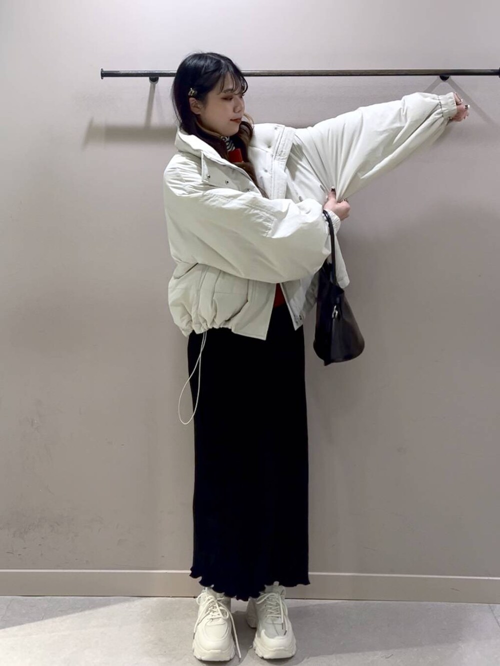 レッド系のニット/セーター、ホワイト系のその他アウター、ブラック系のスカートを着用したレディースの冬コーディネートの9枚目の写真