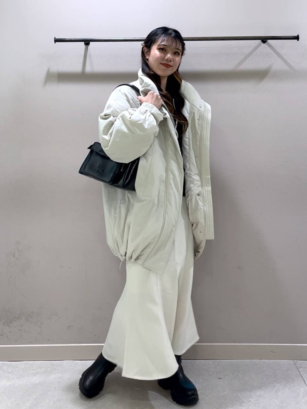 ホワイト系のその他アウター、ブラック系のブーツ、ホワイト系のスカートを着用したレディースの冬コーディネートの8枚目の写真