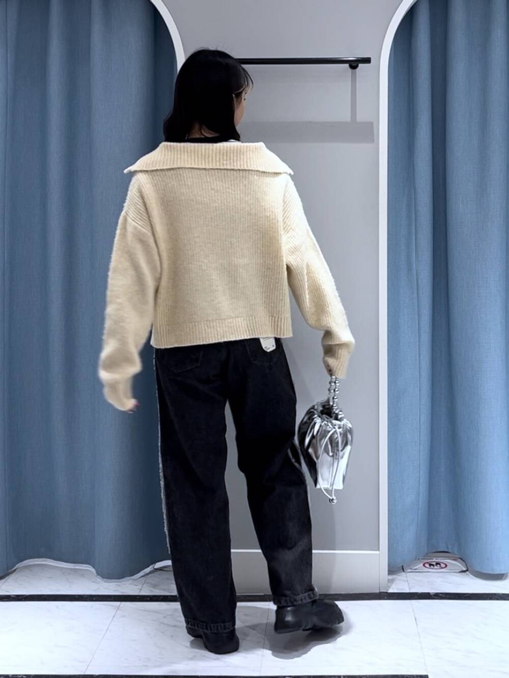 ブラック系のニット/セーター、シルバー系のショルダーバッグ、ブラック系のデニムパンツを着用したレディースの秋コーディネートの4枚目の写真