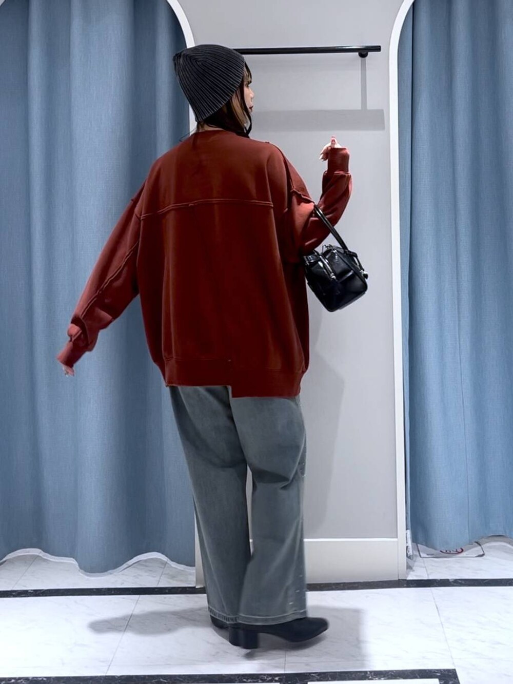 ブルー系のデニムパンツ、ブラック系のブーツ、ブラック系のボストンバッグを着用したレディースの冬コーディネートの5枚目の写真