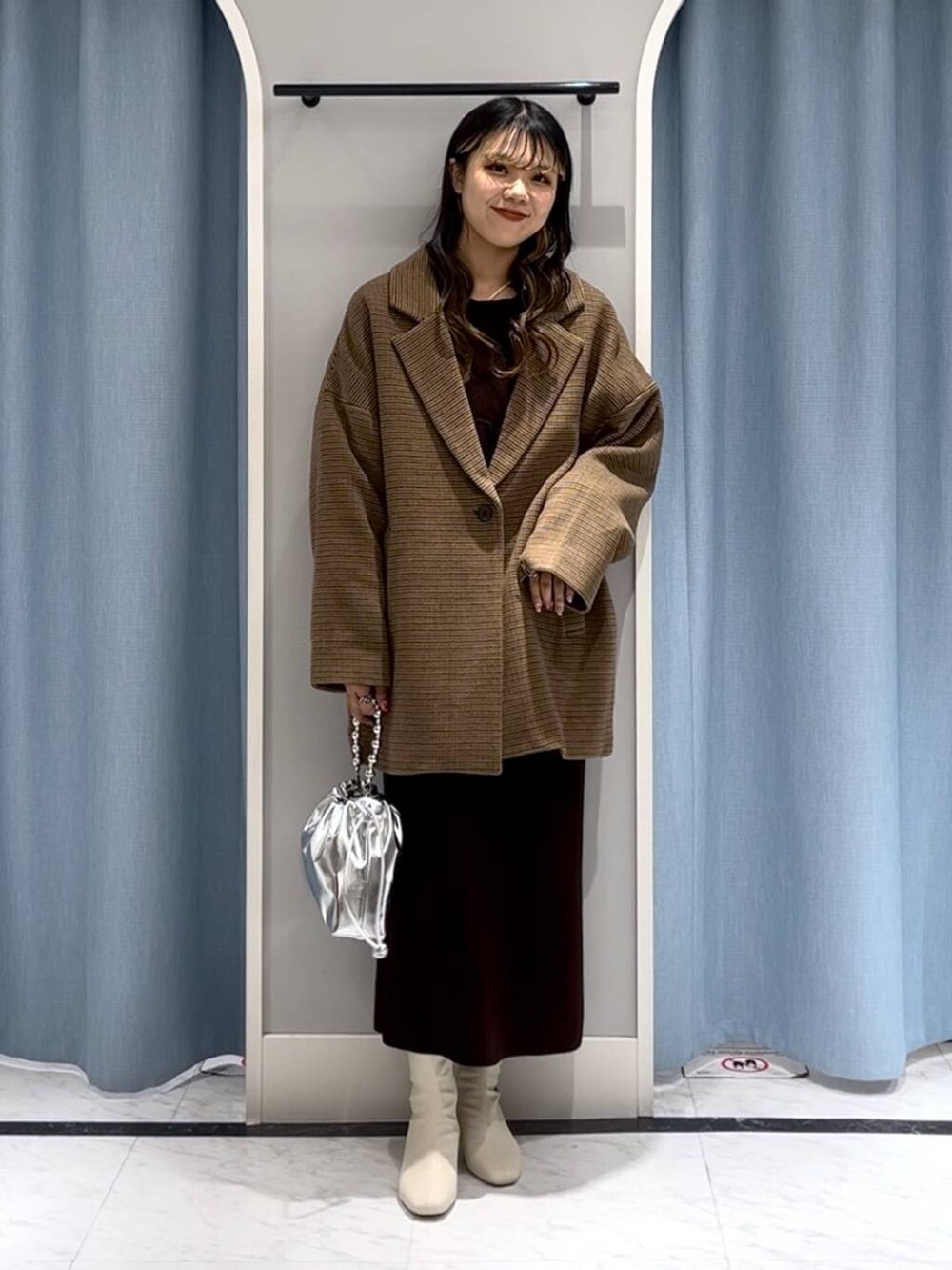 シルバー系のショルダーバッグ、ホワイト系のブーツ、その他のテーラードジャケットを着用したレディースの冬コーディネートの9枚目の写真