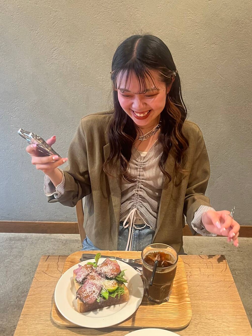 ブルー系のデニムパンツ、ブラック系のパンプス、ブラウン系のテーラードジャケットを着用したレディースの春コーディネートの2枚目の写真